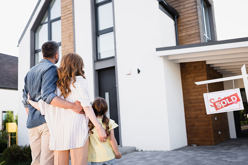 Familie steht vor verkauftem Einfamilienhaus mit Sold-Schild – Haus verkaufen Bad Vilbel erfolgreich mit optimalem Verkaufspreis und professioneller Unterstützung
